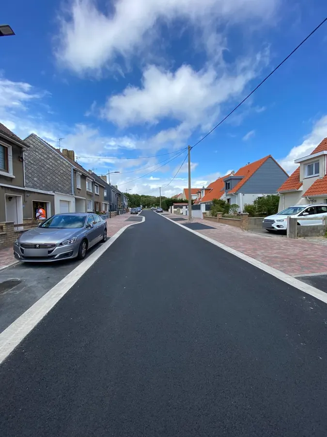 Rue résidentielle revêtue d'un enrobé neuf, trottoirs pavés