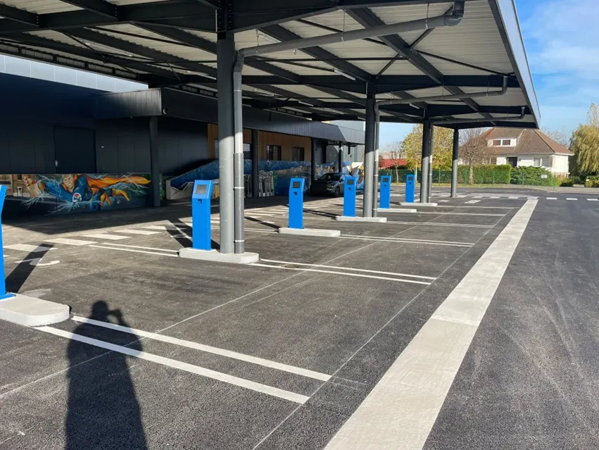 Drive de magasin : voie en enrobé, bornes de commande sous auvent, bordures et marquage au sol