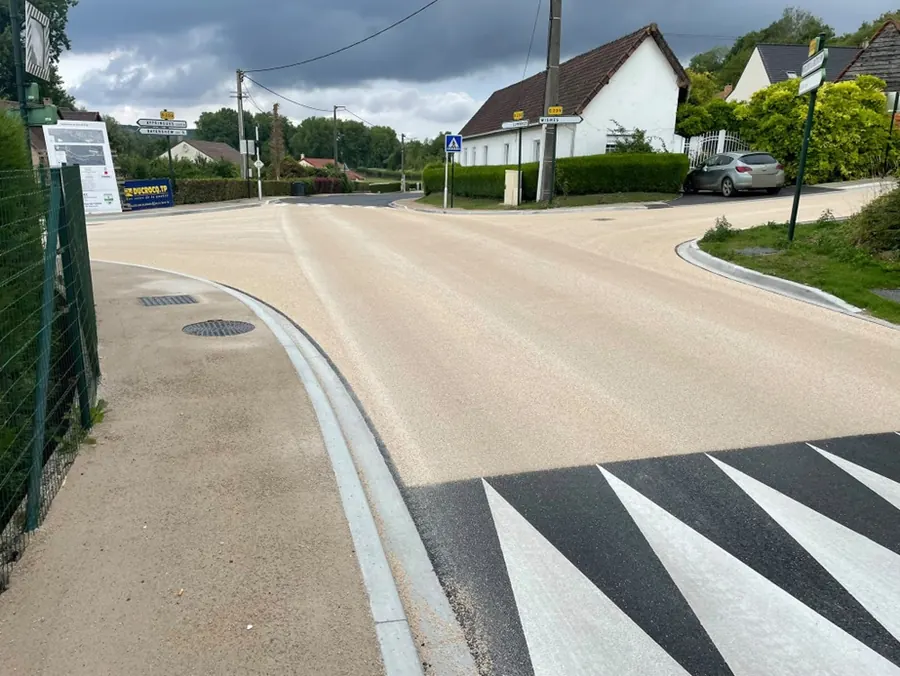Carrefour réaménagé : chaussée en résine claire, bordures neuves et marquage au sol, panneau de chantier Ducrocq TP
