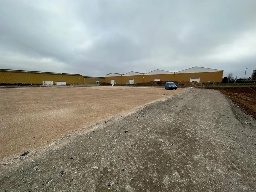 Plateforme de bâtiment en matériaux du Boulonnais réglée au GPS, devant des entrepôts