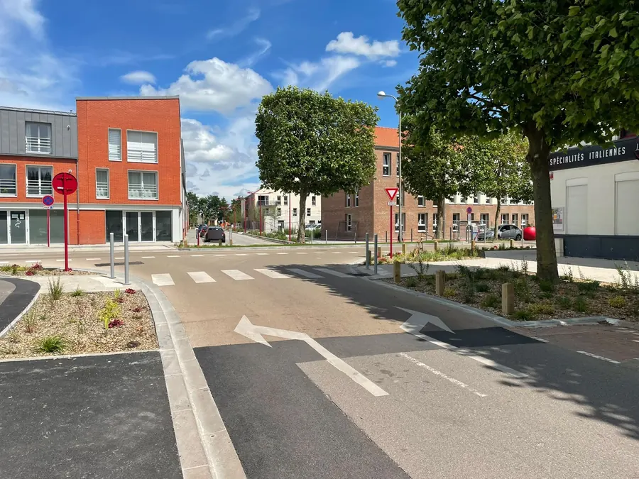 Centre-ville réaménagé : chaussée en enrobé coloré et en enrobé noir, bordures, potelets, plantations et marquage au sol